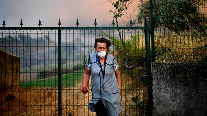 Una aldeana de Sanguinheira se encuentra frente a la puerta de su casa mientras un incendio forestal se acerca a la aldea en Macao, en el centro de Portugal.