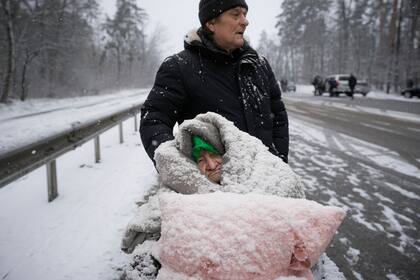 Una anciana, cubierta de nieve, es evacuada en una silla de ruedas de la ciudad de Irpin, en las afueras de Kiev, Ucrania