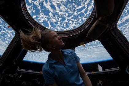 Una astronauta de la NASA mira por la escotilla de la Estación Espacial Internacional a su planeta, la Tierra