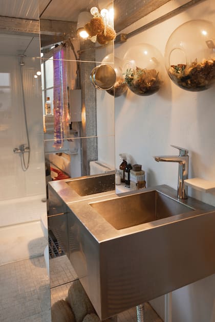 Una bacha de cemento alisado para un baño con espejos que reflejan la luz exterior.