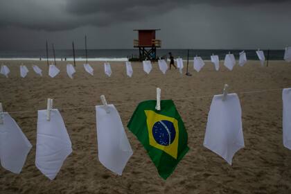 Una bandera brasileña cuelga de un tender en la playa de Copacabana en medio de pañuelos blancos que representan a las personas que han muerto por Covid-19, el viernes 8 de octubre de 2021, en Río de Janeiro