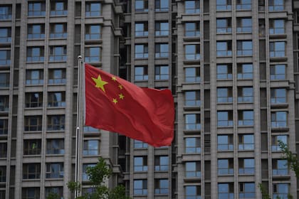 Una bandera nacional china ondea junto a un edificio residencial en Pekín