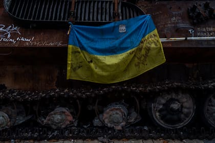 Una bandera ucraniana con mensajes de apoyo a las ciudades del este de Ucrania cuelga de un tanque ruso destruido expuesto en el centro de Kiev, Ucrania, el lunes 7 de noviembre de 2022.