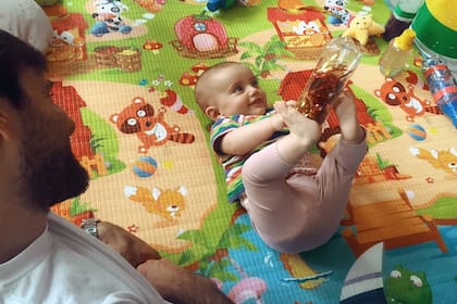 Una bebita de poco más de 5 meses, con ropa cómoda, acompañada por sus padres y apoyada sobre una superficie plana y firme que le permite moverse sin hundirse