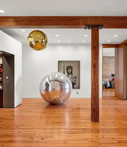 Una bola de espejos colgada del techo aporta un guiño lúdico al diseño del living, mientras que una escultura esférica metálica se exhibe en el piso como pieza decorativa