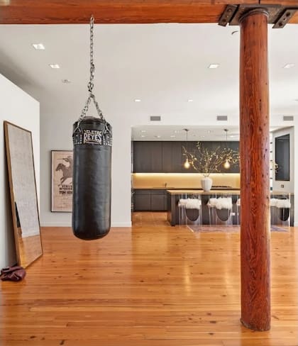 Una bolsa de boxeo cuelga junto a una columna de madera original y un espejo de cuerpo entero