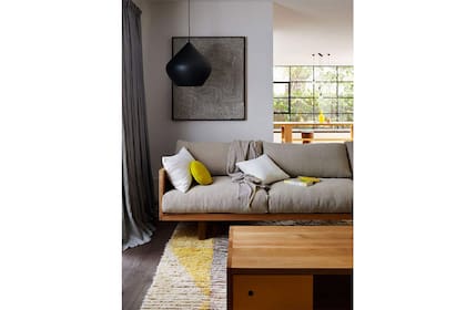 Una caja de madera sostiene almohadones bien mullidos en este living actual