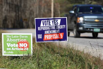 Una camioneta pasa junto a carteles de campaña que se oponen y apoyan una propuesta de enmienda a la constitución de Vermont que garantizaría el acceso a los derechos reproductivos.