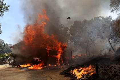 Una casa arde mientras el incendio Oak se mueve por el área el 23 de julio de 2022 cerca de Mariposa, California.