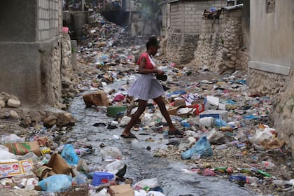 Una chica camina por una calle llena de basura en Puerto Príncipe, Haití, el jueves 13 de julio de 2023