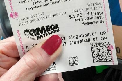Una clienta del Cranberry Super Mini Mart de Cranberry, Pensilvania, muestra su boleto de la lotería Mega Millions