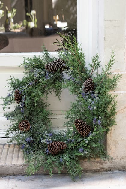 Una corona que puede ir colgado en la puerta o como centro de mesa con velas en el interior para generar un efecto de luz.