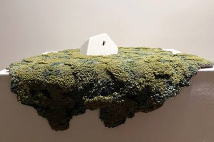 Una de las casas hundiéndose en el paisaje hilado de verdes, azules y amarillos.