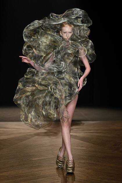 Una de las creaciones
de la holandesa Iris Van Herpen realizada con hilos ultrafinos metálicos que
forman una gran nube de volados ondulantes.