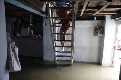 Una de las hijas de Marcela Lanches sube a su dormitorio desde la cocina, totalmente inundada. 
