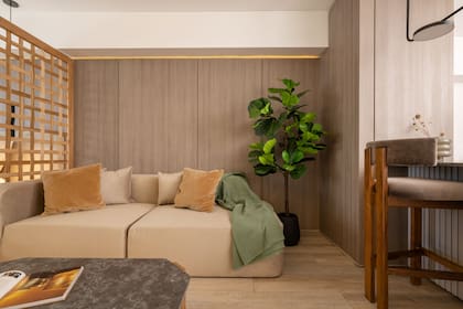 Una de las paredes se recubrió con melamina texturada dentro de la escala de los neutros. El sillón y las sillas de la barra son de pana cruda y gris oscuro (Estudio Aldo).