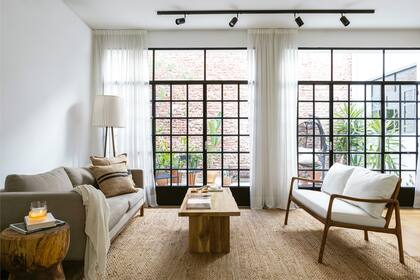 Una decoración planteada por Karina Contini. Alfombra (Mercer). Sillón (Mardeco). Almohadones (Lote Propio). Mesa ‘Longslide’ y sofá ‘Doha’ (Wood Market). Lámpara (Increa). Cortinas (Syria Home).