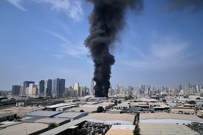 Una densa columna de humo negro se eleva desde un depósito en el área industrial de la ciudad de Sharjah