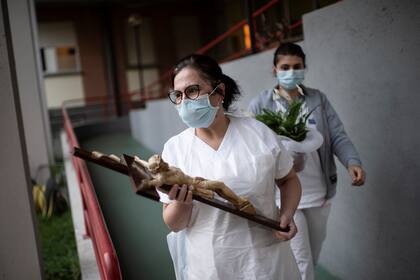 Una enfermera de un hogar para ancianos sostiene un crucifijo el 10 de abril de 2020 en Manta, cerca de Cuneo, en el noroeste de Italia
