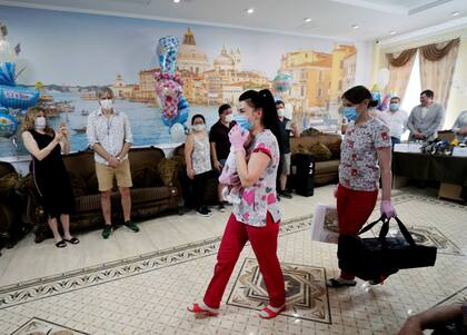 Una enfermera lleva a un recién nacido durante la ceremonia de entrega de niños a sus padres argentinos, en Kiev, Ucrania
