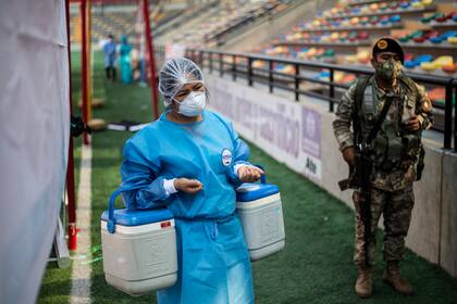 Una enfermera lleva heladeras portátiles con la vacuna desarrollada por Sinopharm contra el coronavirus durante una campaña de vacunación de trabajadores de la salud, en Ate, un distrito de Lima