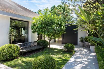 Una entrada lateral atraviesa el jardín hasta el portón corredizo que desemboca directamente en la zona de la parrilla.