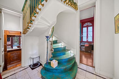 Una escalera caracol de tono turquesa desgastado aporta un toque moderno y vibrante al ambiente. 