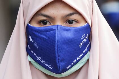 Una estudiante tailandesa con un barbijo con el mensaje "lucharemos juntos", abandona su dormitorio de la Universidad del Príncipe de Songkla después de cumplir una cuarentena obligatoria de 14 días en la provincia sureña de Pattani en Tailandia el 13 de abril de 2020