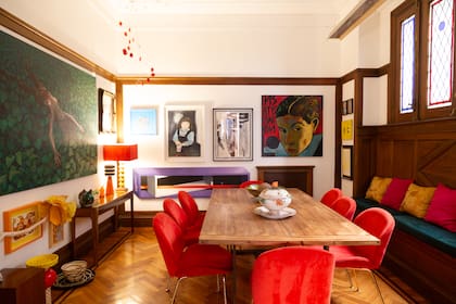 Una extensa mesa de madera y ocho sillas Thea tapizadas en pana color rojo se ubican en el centro del ambiente exclusivo del comedor. 