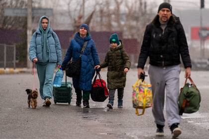 Una familia camina por una carretera mientras huyen de su vecindario, en las afueras de Kiev, Ucrania