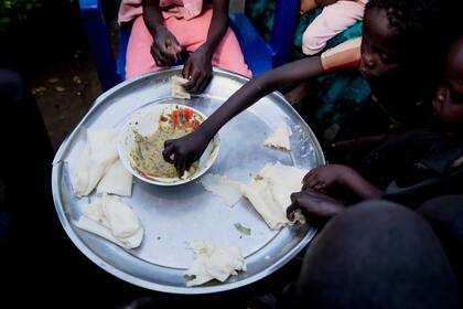 Una familia comparte la única comida del día en su casa en Juba, Sudán del Sur, el martes 27 de mayo de 2021. (AP Foto/Adrienne Surprenant)