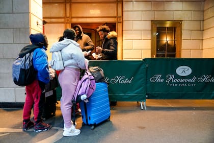 Una familia de migrantes muestra su documentación a los guardias de seguridad en el Hotel Roosevelt, el martes 9 de enero de 2024, en la ciudad de Nueva York. (AP Foto/Mary Altaffer)