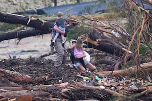 Una familia intenta cruzar el río Guadalupe luego de que una inundación repentina azotara la zona, el 5 de julio de 2025, en Ingram, Texas. (AP Foto/Julio Cortez)