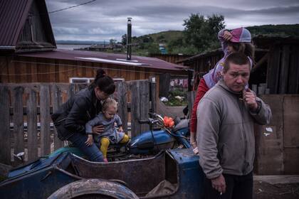 Una familia junto a su sencilla vivienda en Takhta, junto al río Amur