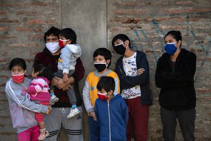 Una familia observa cómo los trabajadores municipales desinfectan un barrio de Santiago, el 16 de mayo de 2020, en medio de la cuarentena total obligatoria debido a la pandemia de coronavirus