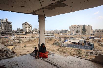 Una familia palestina sentada en los restos de su casa dañada en un bombardeo israelí anterior, mientras algunos residentes regresan a la ciudad de Khan Younis, en el sur de la Franja de Gaza, el 30 de junio de 2024, en medio del conflicto en curso entre Israel y el grupo militante palestino Hamas.