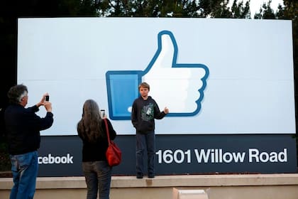 Una familia se toma una foto frente al cartel que indica la ubicación del cuartel general de Facebook en California