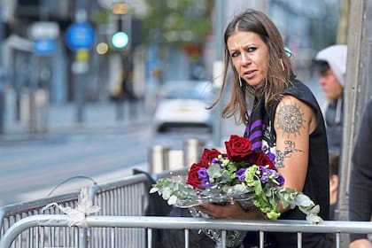 Una fan se acerca al puente de Black Sabbath para dejar un arreglo floral