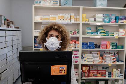 Una farmacéutica usa un barbijo mientras espera a los clientes en una farmacia en San Fiorano, una de las ciudades encerradas debido a un brote de coronavirus