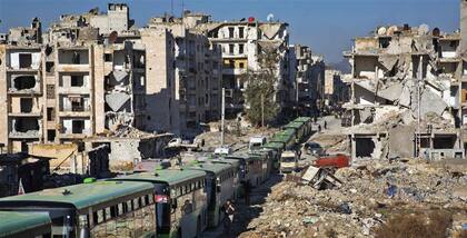 Una fila de ómnibus deja la ciudad en el primer día de evacuación de los barrios rebeldes arrasados