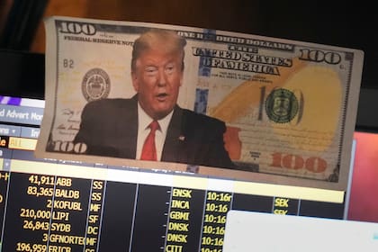 Una fotografía del presidente estadounidense Donald Trump sobre un billete de cien dólares es exhibida en el piso de la Bolsa de Valores, el martes 21 de enero de 2025, en Nueva York. (AP Foto/Seth Wenig)