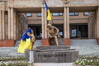 Una fotografía tomada el 10 de septiembre de 2022 muestra banderas ucranianas colocadas en estatuas en una plaza de Balakliya, en la región de Kharkiv, en medio de la invasión rusa de Ucrania.