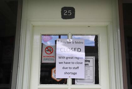 Una fotografía tomada el 20 de junio de 2022 muestra un mensaje de cierre por falta de personal expuesto en el escaparate de una tienda, en el centro de la ciudad de Keswick, en el Distrito de los Lagos, al noroeste de Inglaterra. 