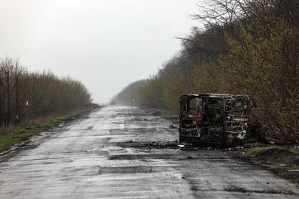 Una furgoneta quemada es fotografiada en el camino vacío hacia Popasna, la región ucraniana de Donbass, el 14 de abril de 2022 en medio de la invasión rusa de Ucrania. 