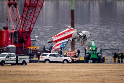 Una grúa descarga una pieza de los restos de un buque de salvamento en un camión de plataforma, cerca del lugar de los restos en el río Potomac de una colisión en pleno vuelo entre un avión de American Airlines y un helicóptero Black Hawk, en el Aeropuerto Nacional Ronald Reagan de Washington, el miércoles 5 de febrero de 2025, en Arlington, Virginia.
