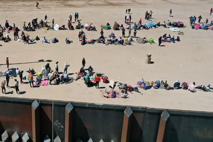 Una imagen aérea muestra a los migrantes que esperan a lo largo del muro fronterizo para entregarse a los agentes de la Patrulla Fronteriza de Aduanas y Protección Fronteriza (CBP, por sus siglas en inglés) de EE. UU. para el procesamiento de solicitudes de inmigración y asilo después de cruzar el Río Grande hacia Estados Unidos, en la frontera entre Estados Unidos y México en El Paso, Texas, el 11 de mayo de 2023