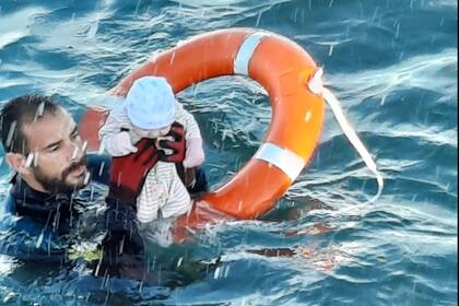Una imagen publicada por la Guardia Civil española el 18 de mayo de 2021 muestra a un miembro de la Guardia Civil española sosteniendo a un bebé migrante en el agua frente a la costa del enclave español de Ceuta