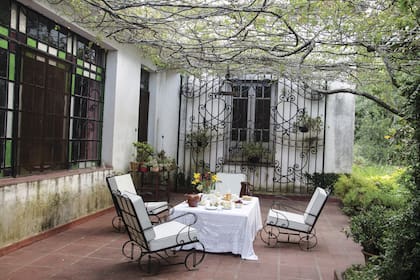 Una imagen típica de estancia: la mesa de té bajo un rosal de más de 80 años. Contra la ventana, antigua reja de entrada al campo.