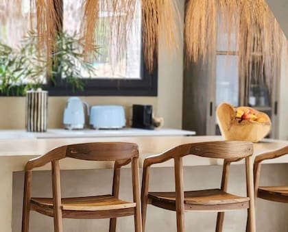 Una isla rodeada de banquetas de madera (RGA Deco by Sagitario) es el punto de reunión cotidiano de la familia.