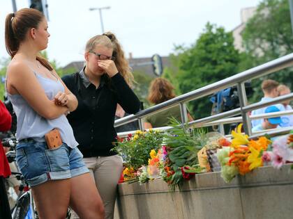 Una joven llora junto a las ofrendas florales
